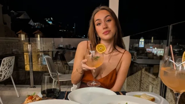 Сафрон Леггатт позує за столом з коктейлем та двома великими тарілками перед собою