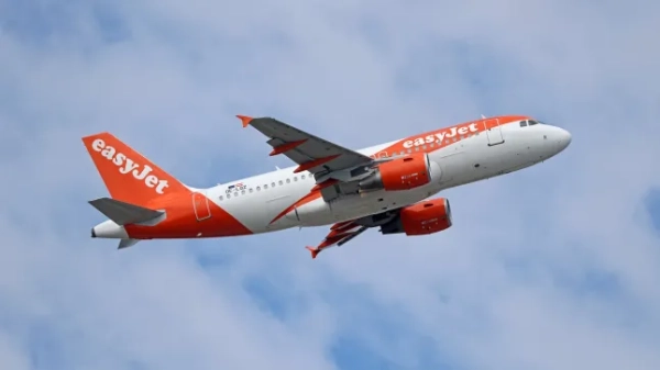 Літак easyJet летить на тлі блакитного хмарного неба.