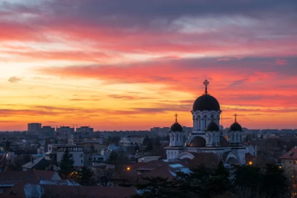 Міський вид на Бухарест, Румунія, у сутінках, з рожевими та помаранчевими хмарами.