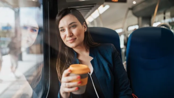 Бізнес-леді сидить у поїзді та тримає чашку кави