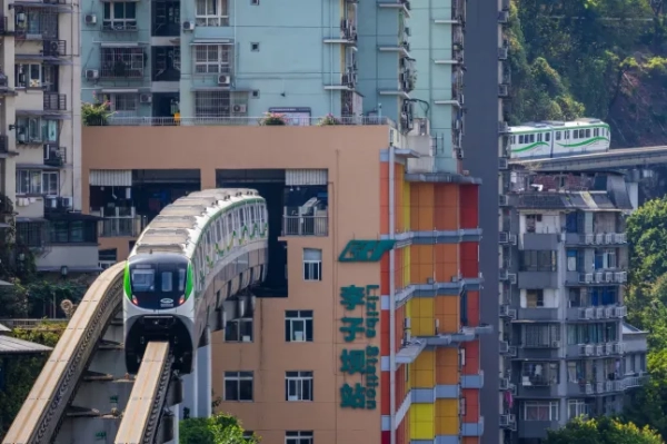 ЧУНЦИН, КИТАЙ – 17 ВЕРЕСНЯ: Два монорейкові поїзди Chongqing Rail Transit під'їжджають до станції Лізіба з протилежних напрямків, демонструючи унікальний дизайн, де поїзди проходять через житловий будинок, 17 вересня 2024 року в Чунціні, Китай. (Фото Cheng Xin/Getty Images)