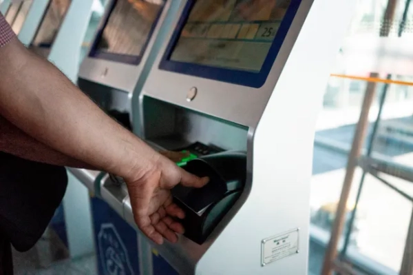 У мандрівника знімають відбитки пальців на сканері в аеропорту.