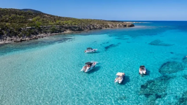 Кіпрська Блакитна Лагуна поблизу села Лачі-Латсі на узбережжі Національного лісового парку Акамас. Вид з дрона на невеликі туристичні моторні човни, що стоять на якорі в бірюзово-блакитній лагуні Національного лісового парку Акамас, північно-західне узбережжя Кіпру. Блакитна Лагуна, Лачі-Латсі, Національний лісовий парк Акамас, північно-західне узбережжя грецької частини Кіпру, район Пафос, острів Кіпр, середземноморський острів.