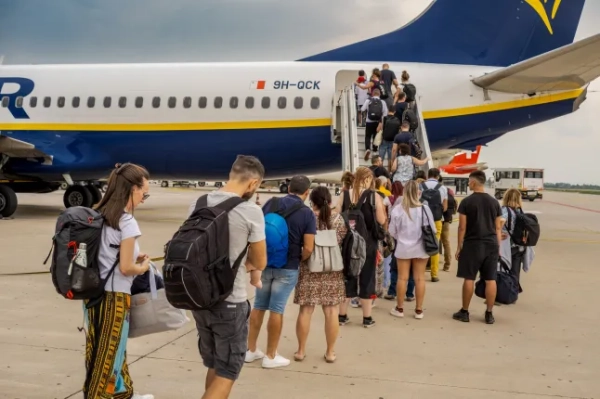 Люди стоять у черзі поруч із літаком Ryanair в аеропорту та піднімаються по сходах.