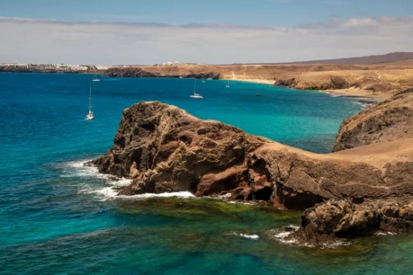 Вид з повітря на вітрильники в затоці, маленькі пляжі та оглядовий майданчик пляжу Плайя-де-Папагайо, Плайя-Бланка, Лансароте, Канарські острови, Іспанія