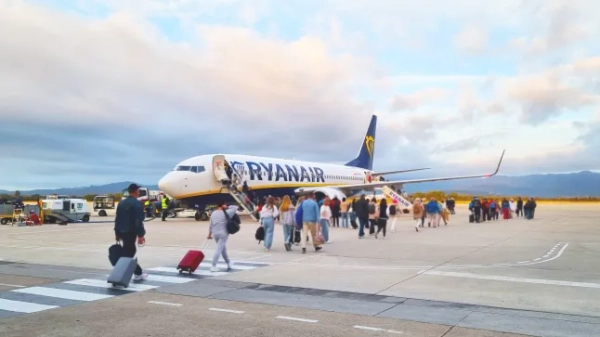 Пасажири йдуть по злітній смузі аеропорту до літака Ryanair.