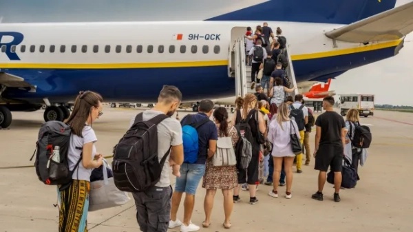 Люди стоять у черзі поруч із літаком Ryanair в аеропорту та піднімаються по сходах.