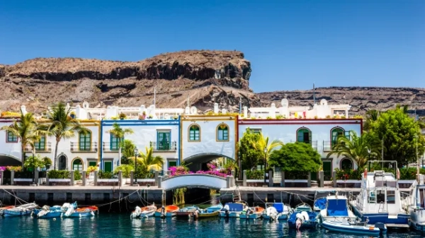 Ряд білих будівель на пристані для яхт з океаном і човнами попереду в Могані, Гран-Канарія.