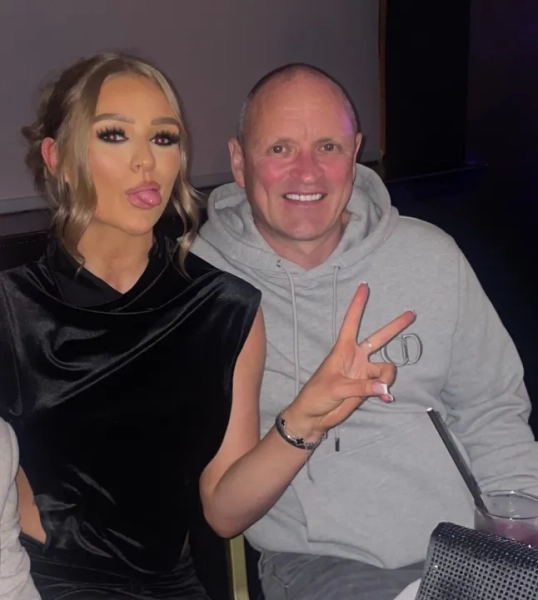 Донька, показавши язика, робить жест миру руками, на фото з батьком.