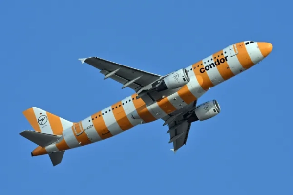 Помаранчево-білий Airbus німецької авіакомпанії Condor летить крізь блакитне небо.