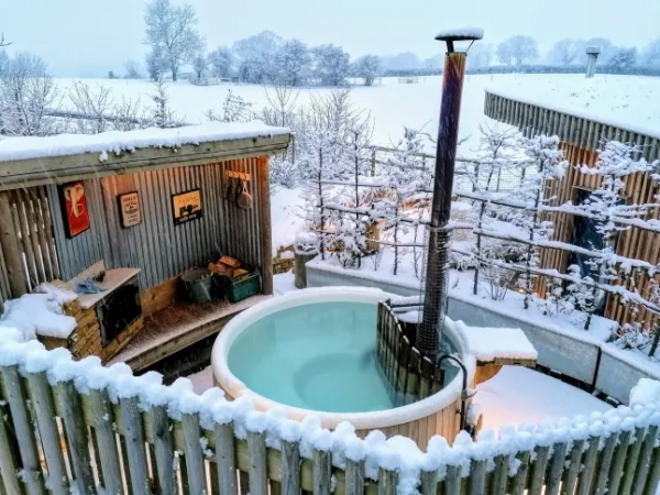 Сніжний пейзаж у готелі Malvern Hills Lodge у Вустерширі, де сніг покриває сауну, дерев'яну терасу та гідромасажну ванну.